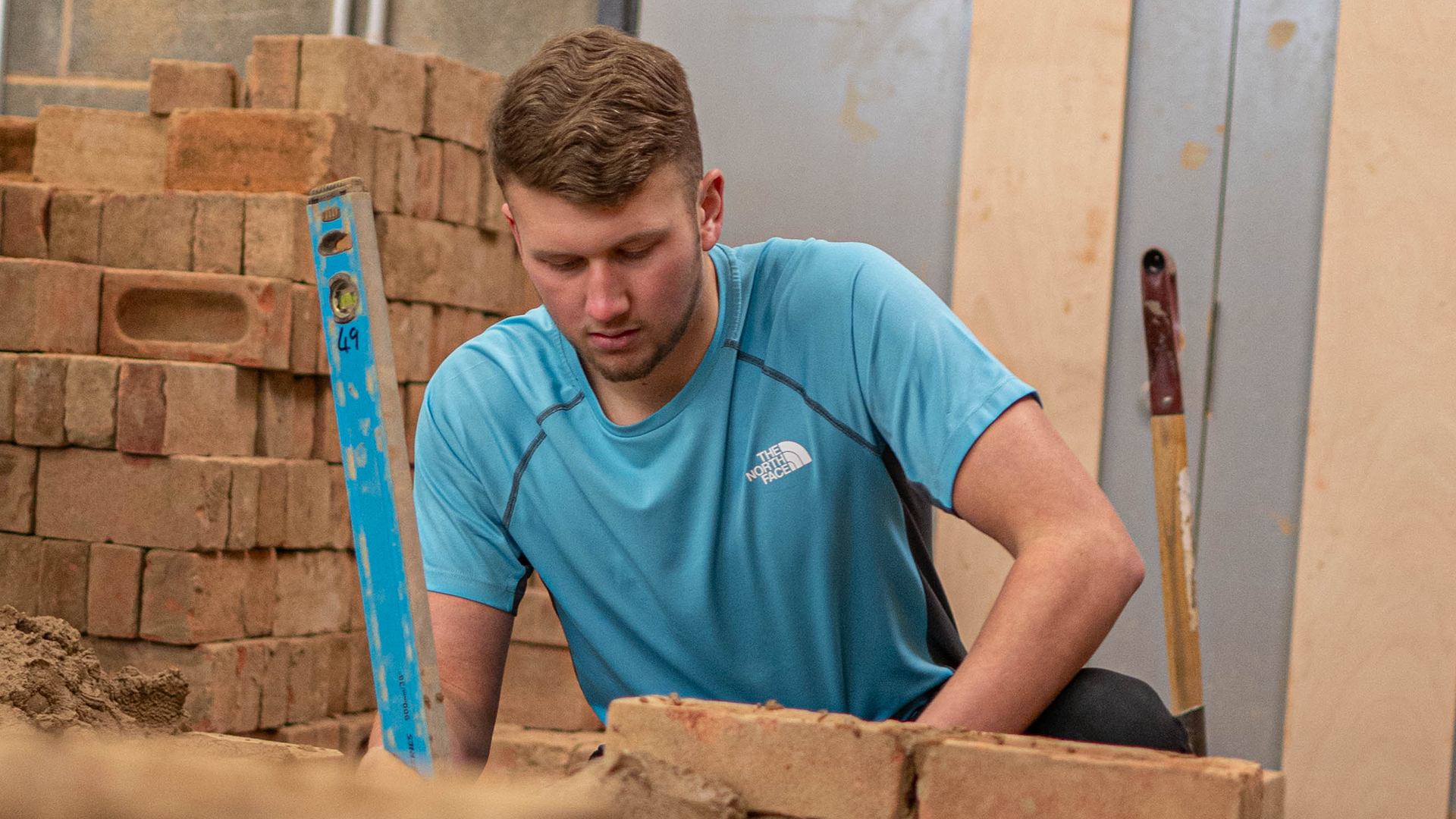 Student holding spirit level next to stack of bricks.