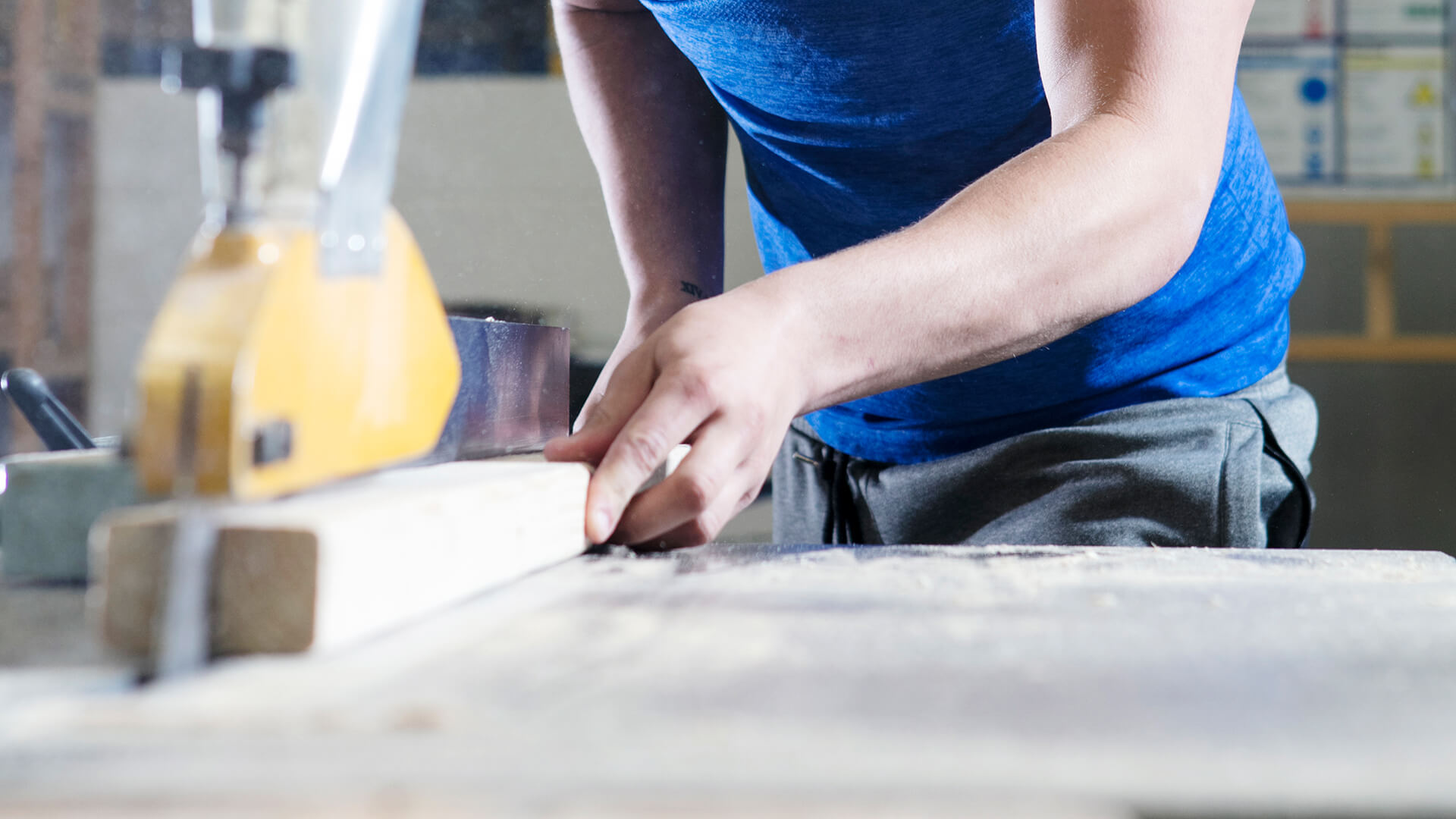 Hands on a work bench, cutting a piece of wood.