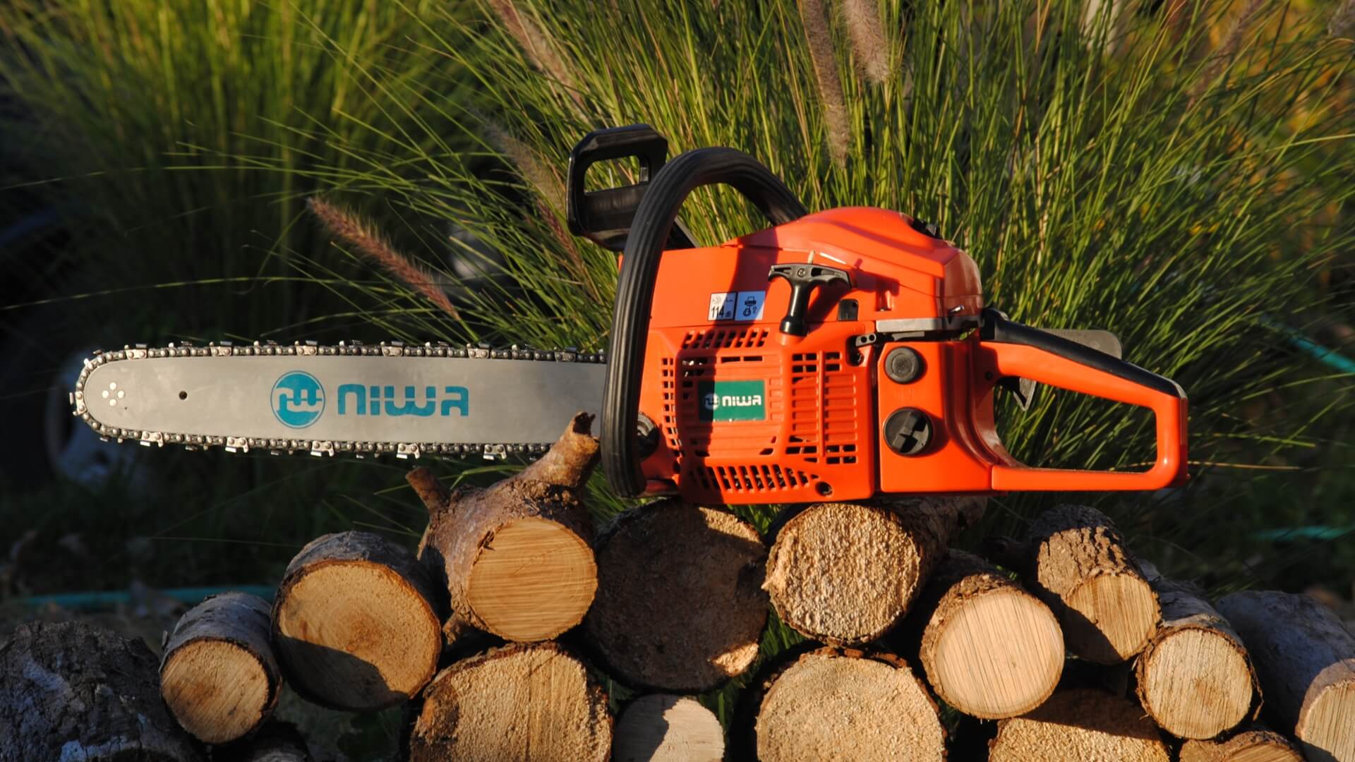 Chainsaw resting on pile of chopped logs.