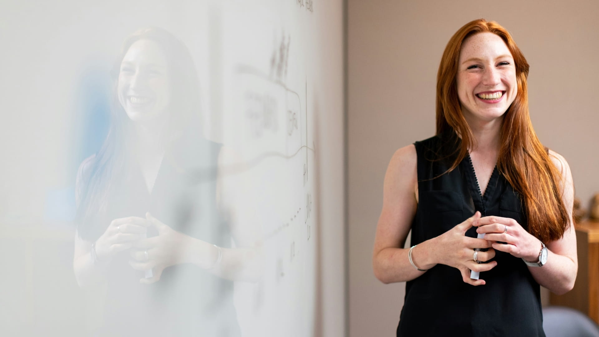 Teacher standing smiling next to whiteboard