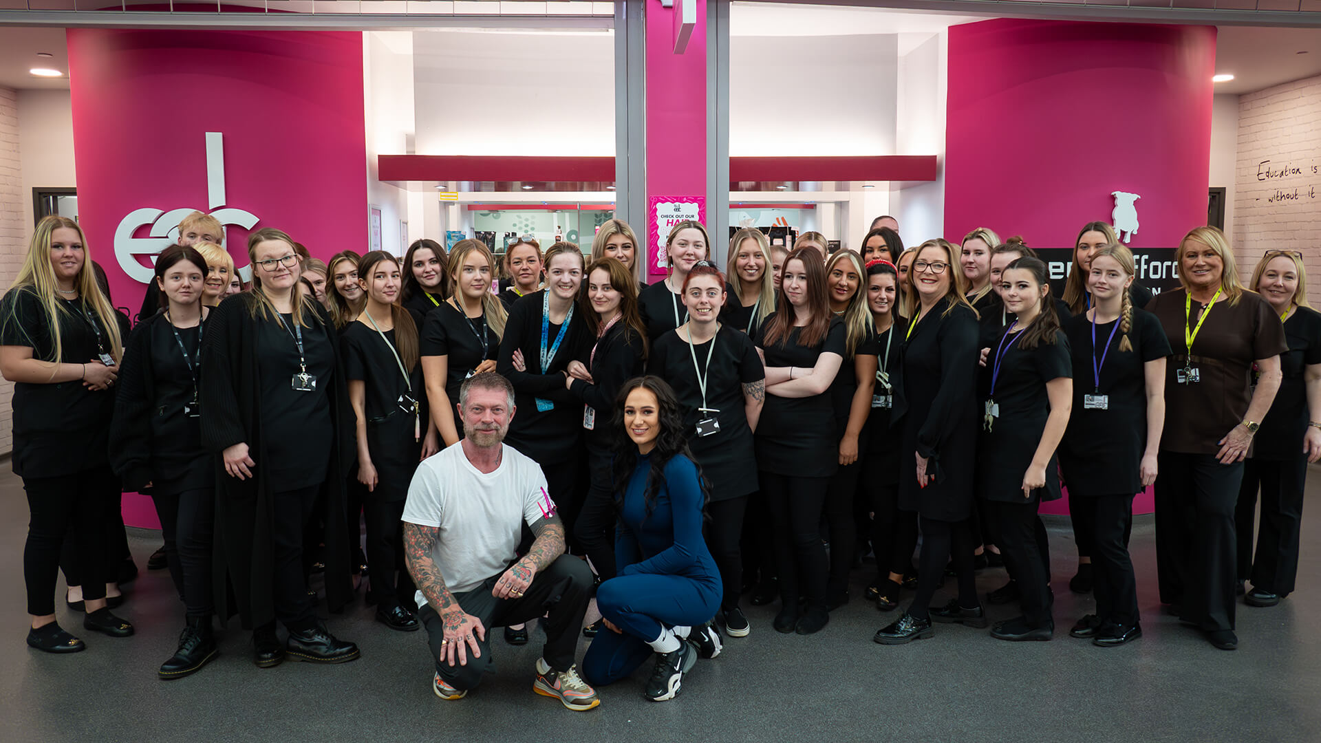 A group shot of students, staff and celebrity hair stylist, Lee Stafford, standing in front of the entrance of East Durham College's hair and beauty salon.