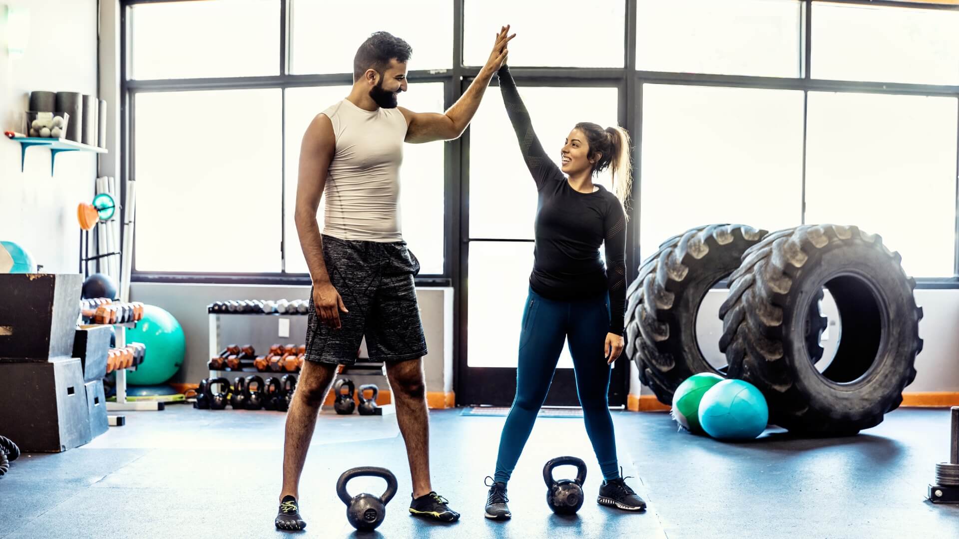 Woman training a man how to do a push up in a gym.