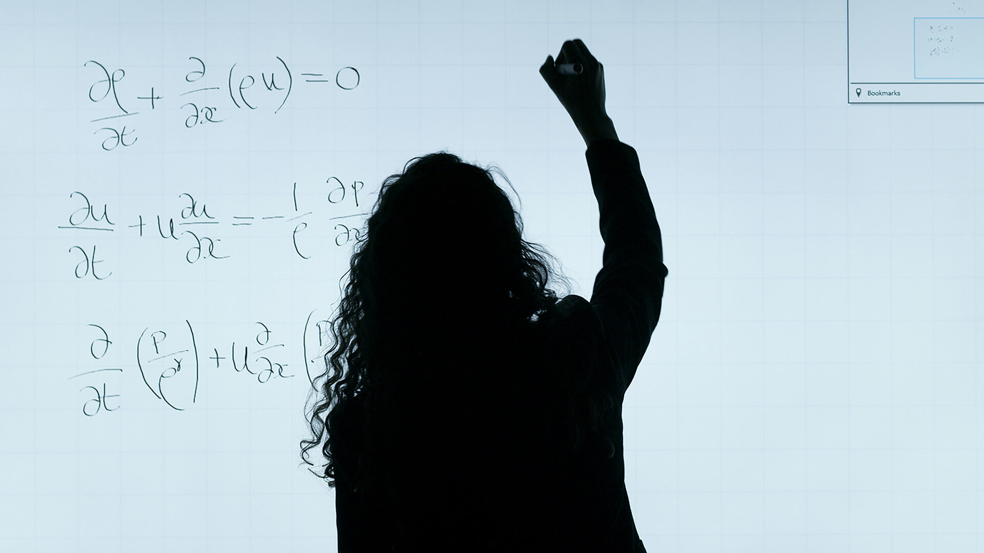 Students holding textbooks in front of a large whiteboard which has numerous of sums wrote on it.