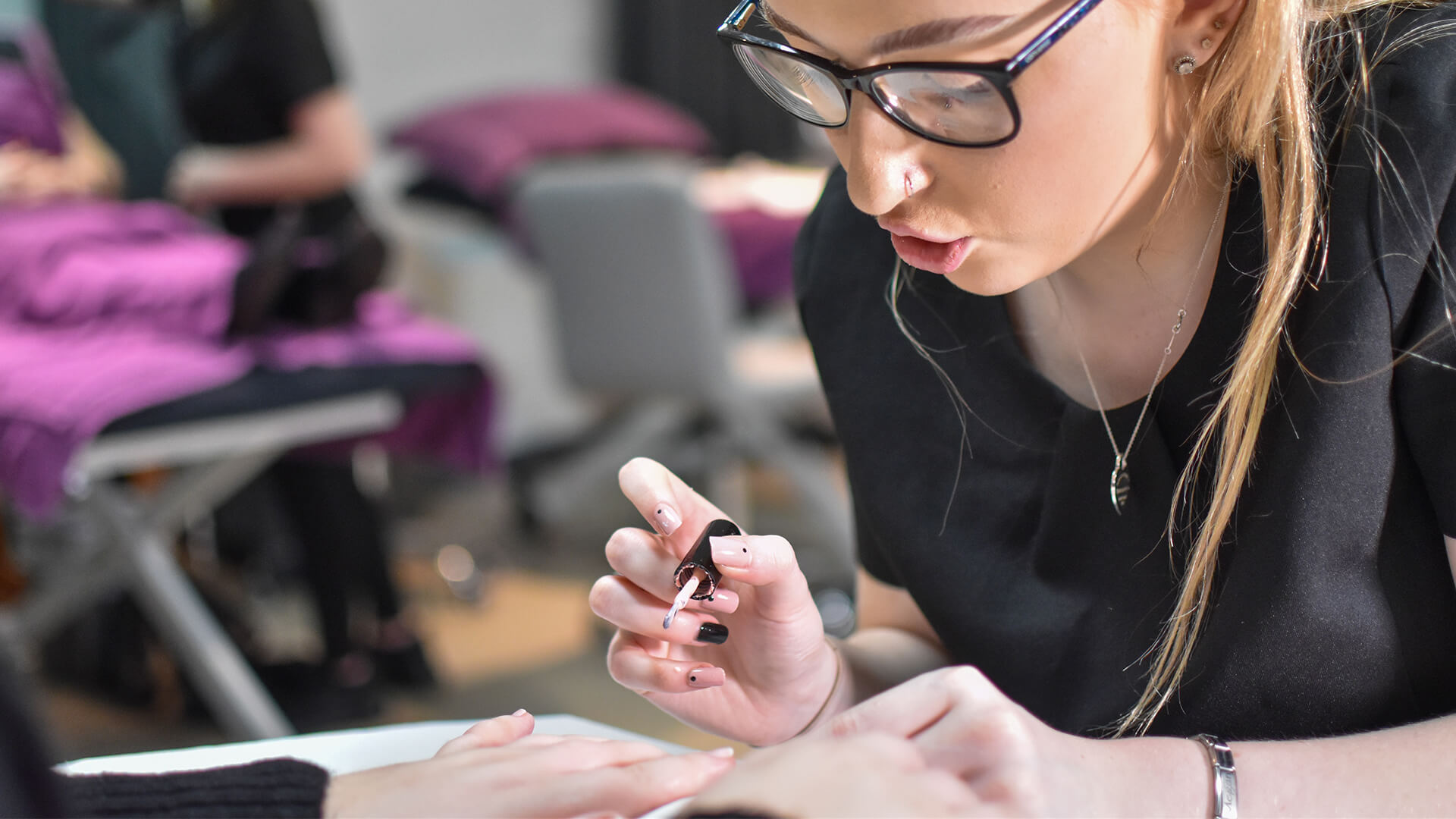 Young woman painting another persons nails.