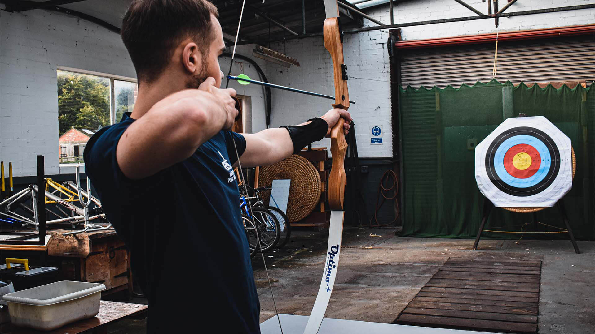 A Man holding a bow and arrow, shooting at a target.