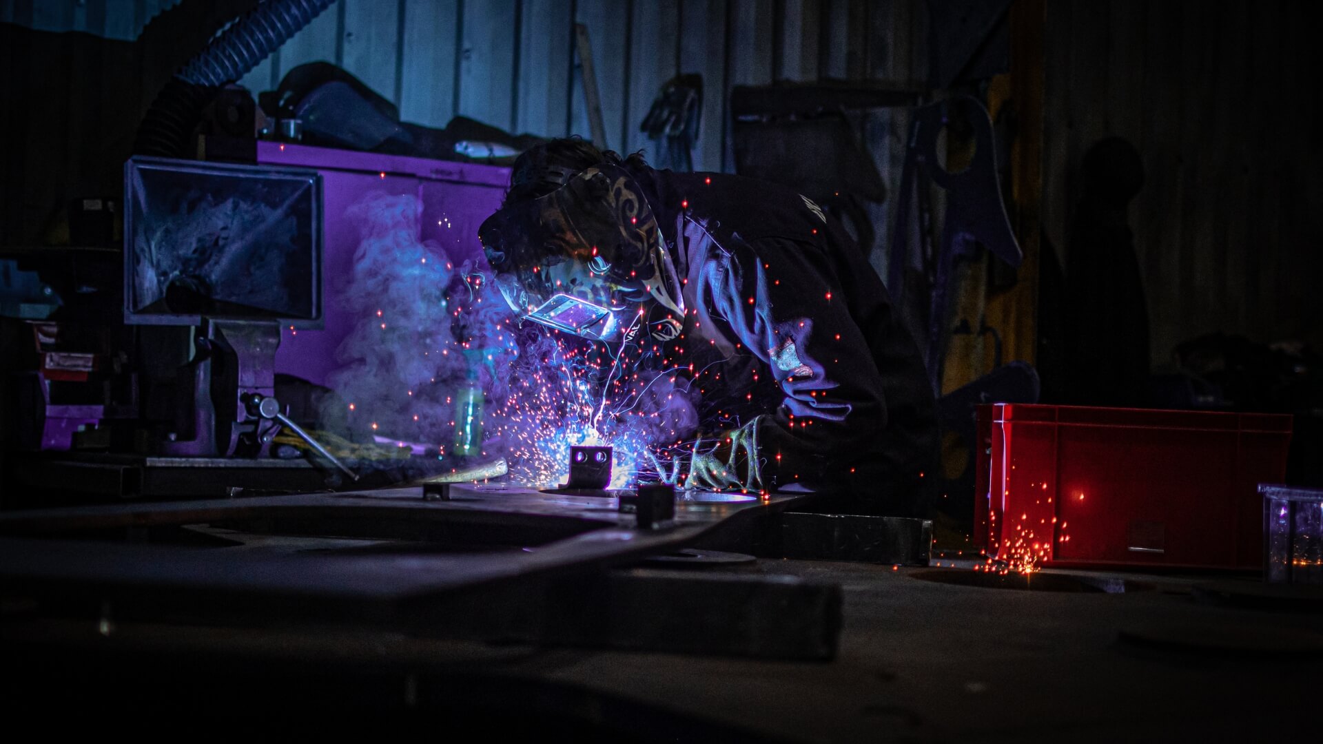Engineer in full PPE and welding mask welding and creating sparks