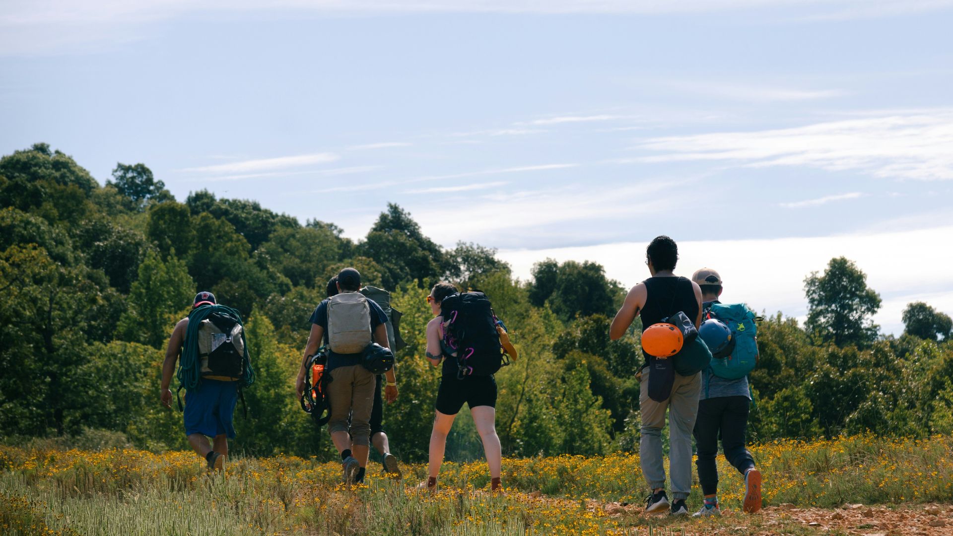 Group of people walking outside wearing large backpacks
