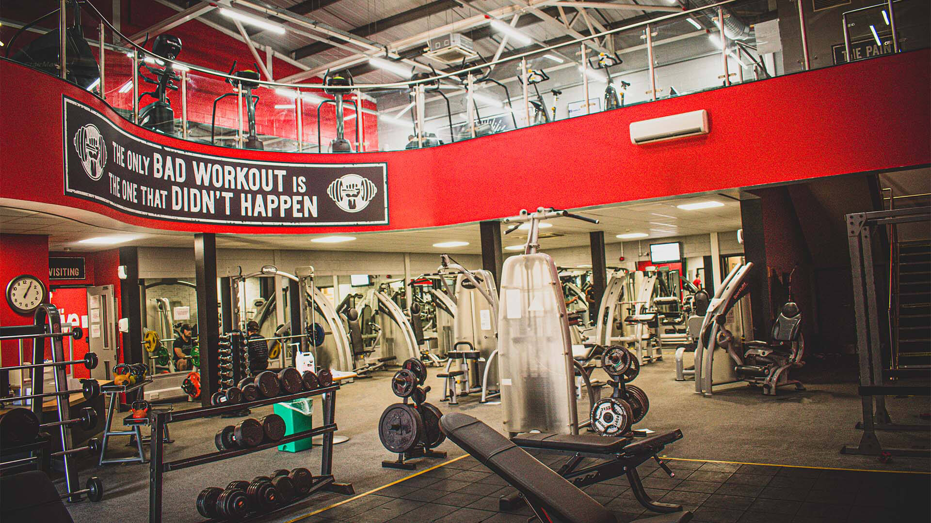 A two story gym with various equipment like weights, treadmills and benches.