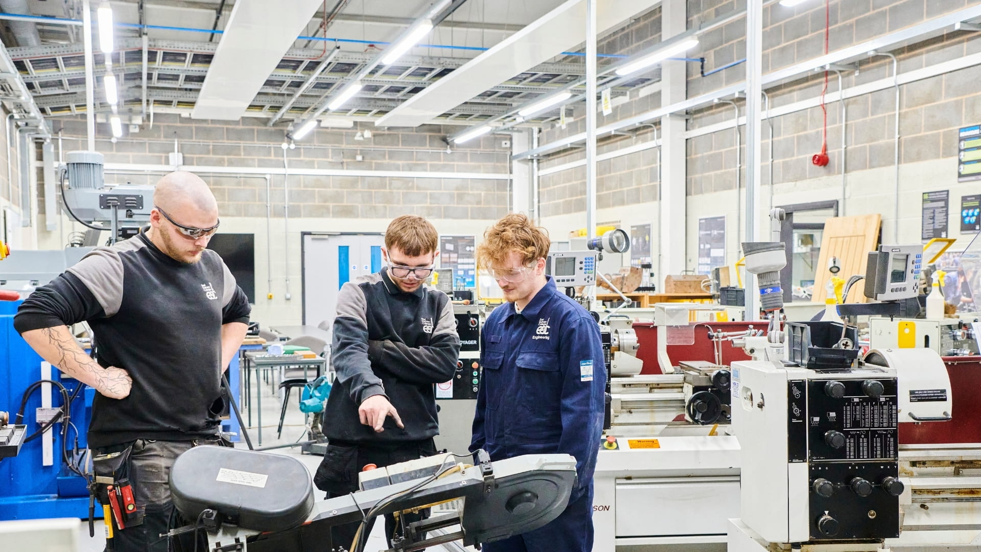 Student and two teachers looking at machinery together