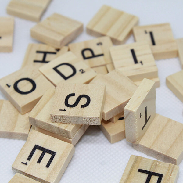 Scrabble letter tiles in a pile on a white desk.
