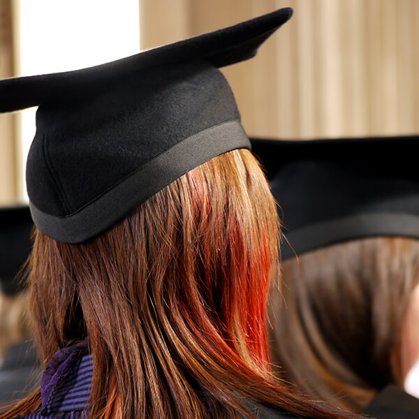The back of a woman's head wearing a graduation cap.