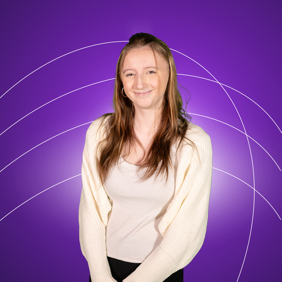 Young women standing smiling at camera on a purple background.