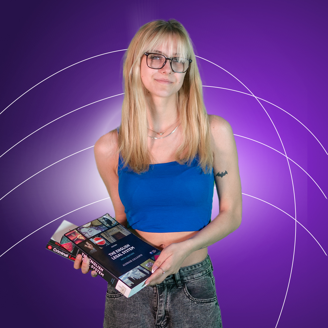 Young women holding Law textbooks smiling at camera on a purple background.