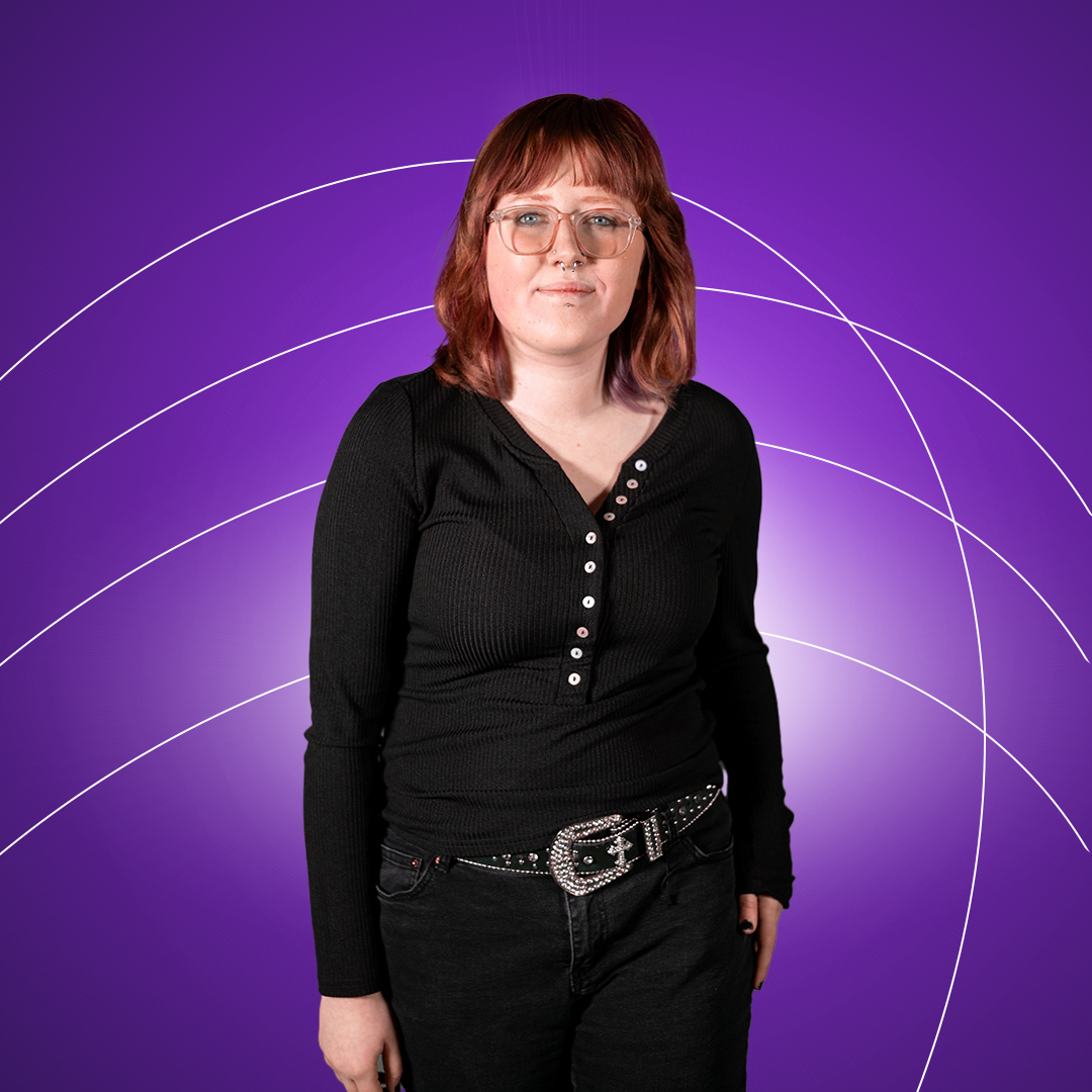 Young women standing smiling at camera on a purple background.