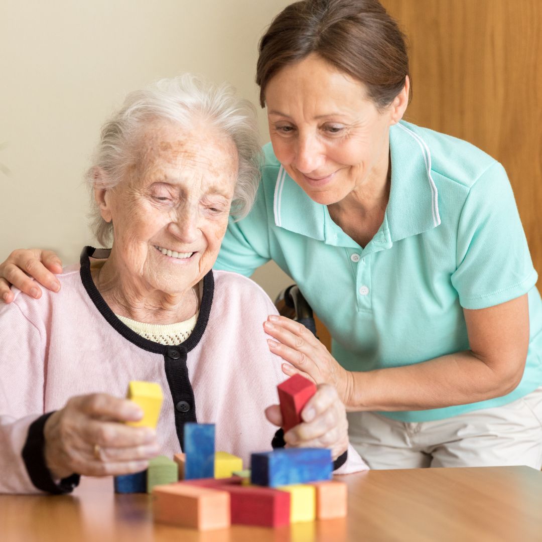 Nurse helping an older woman building blocks