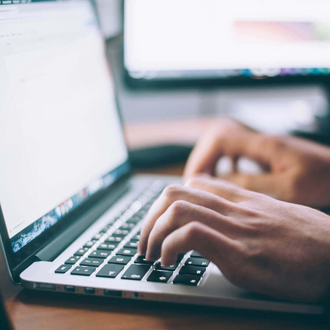 Close up of someones hands typing on laptop.
