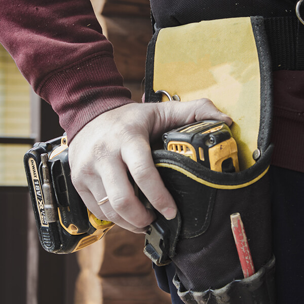A hand holding a drill that is a work belt.