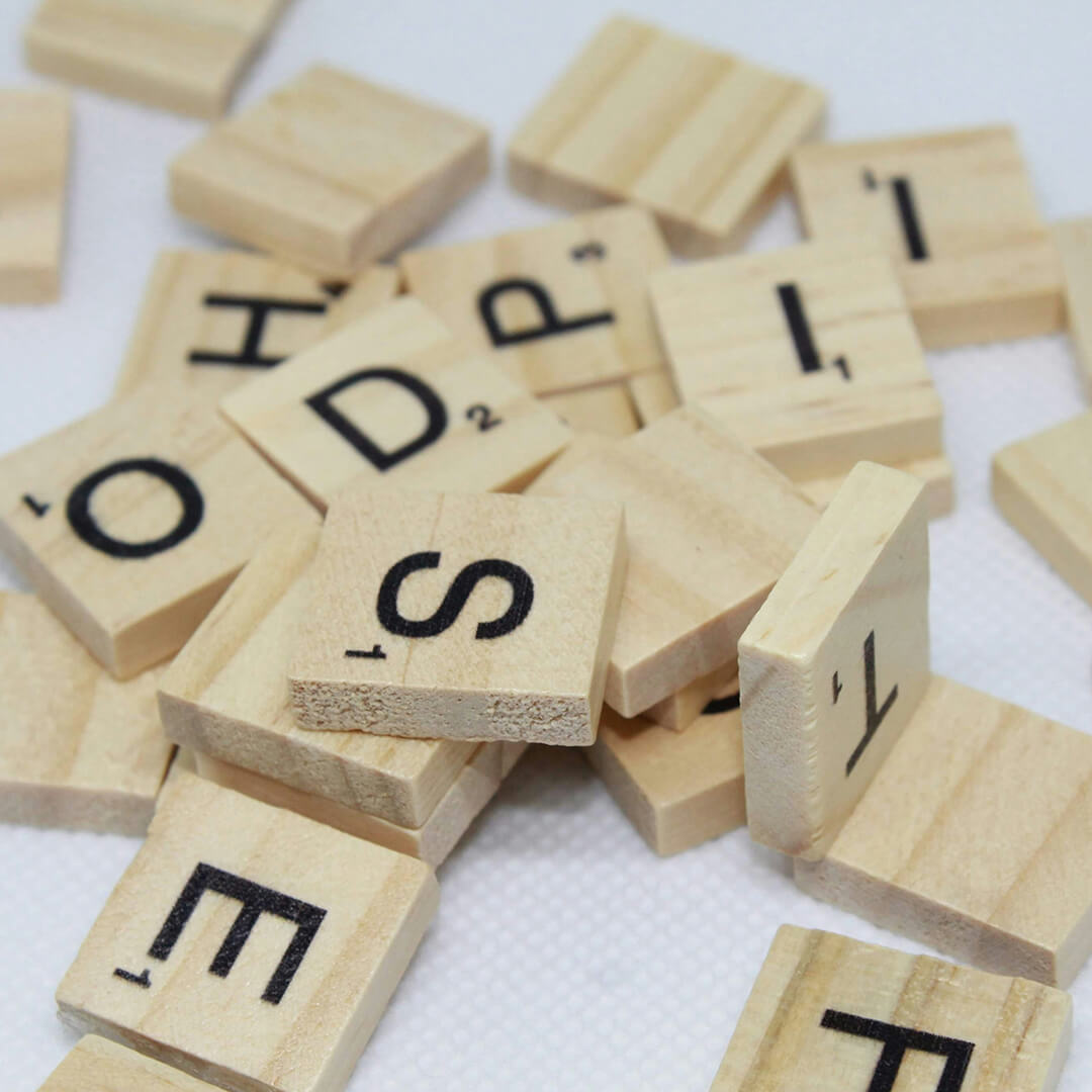 Scrabble letter tiles in a pile on a white desk.