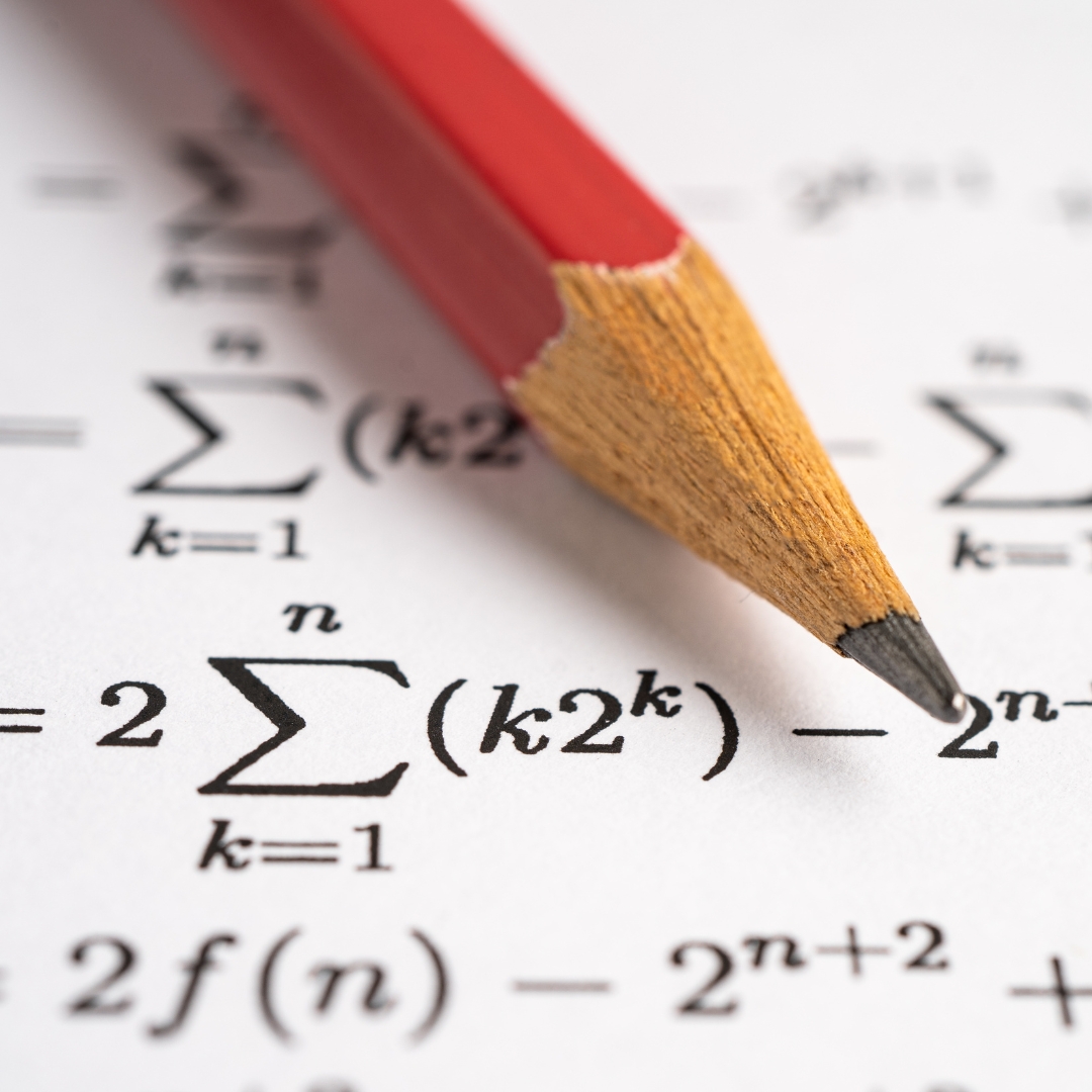 Pencil resting on page of maths equations.