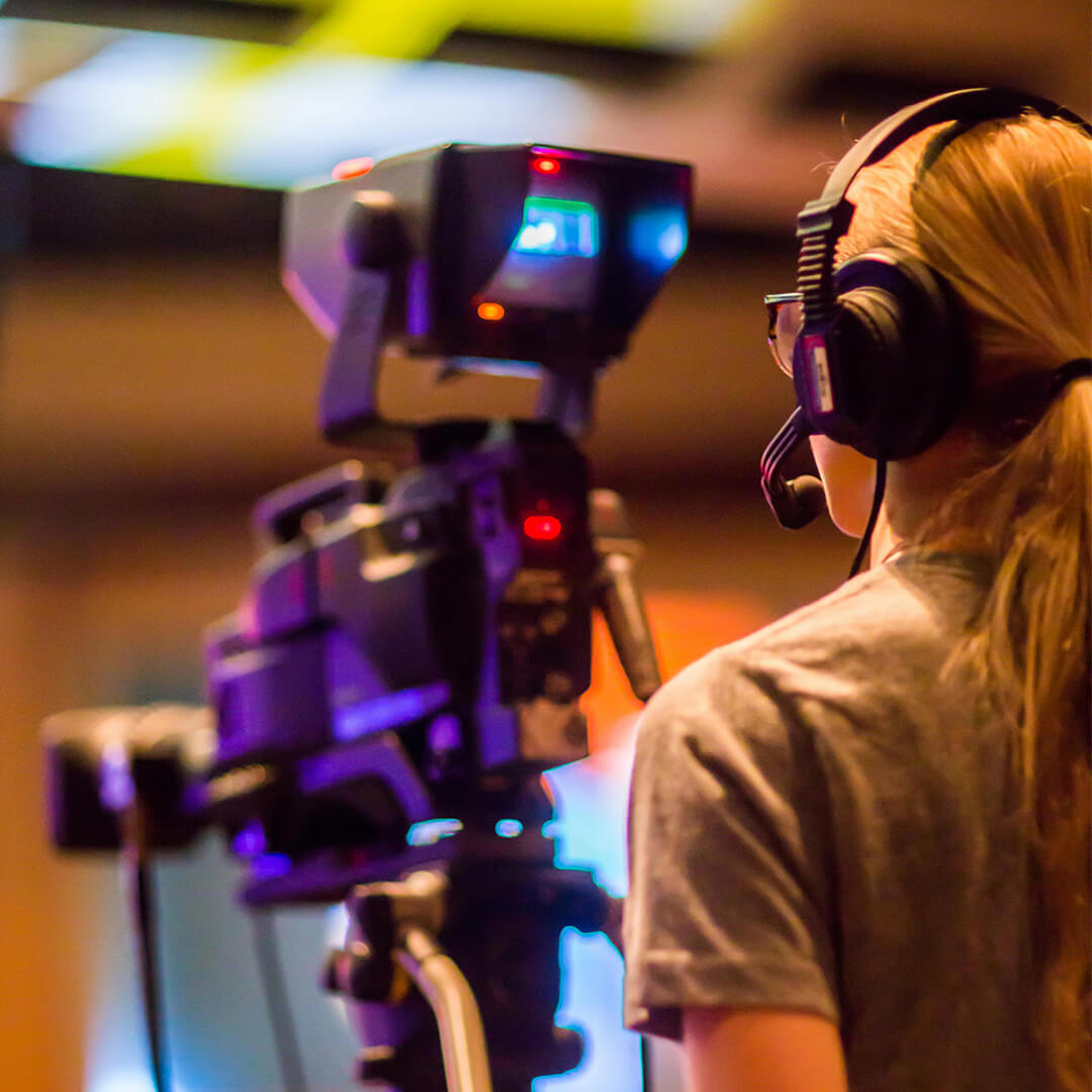 Young woman working with a camera on a stand.