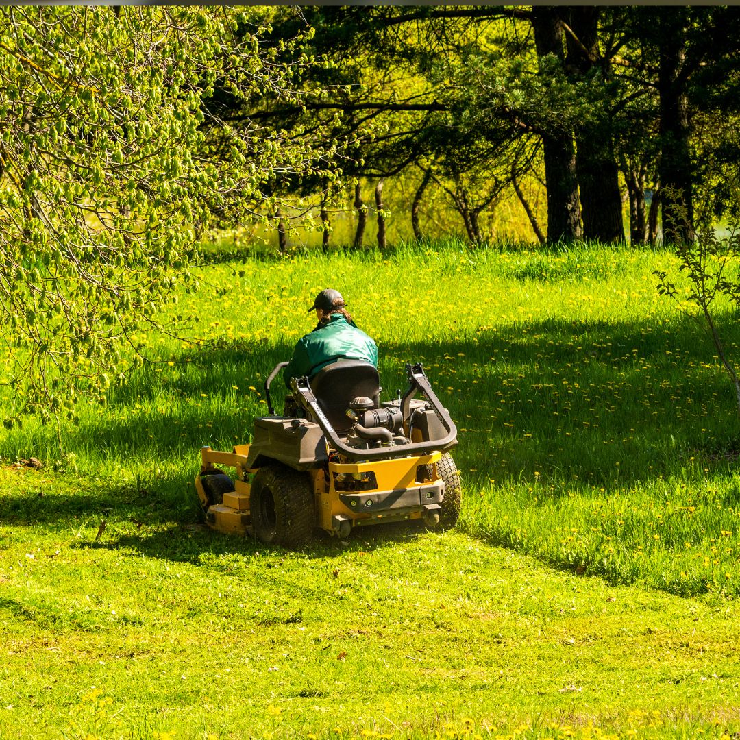 Man riding a ride on mower in a field.
