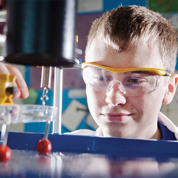 Young man wearing safety goggles doing a science experiment.