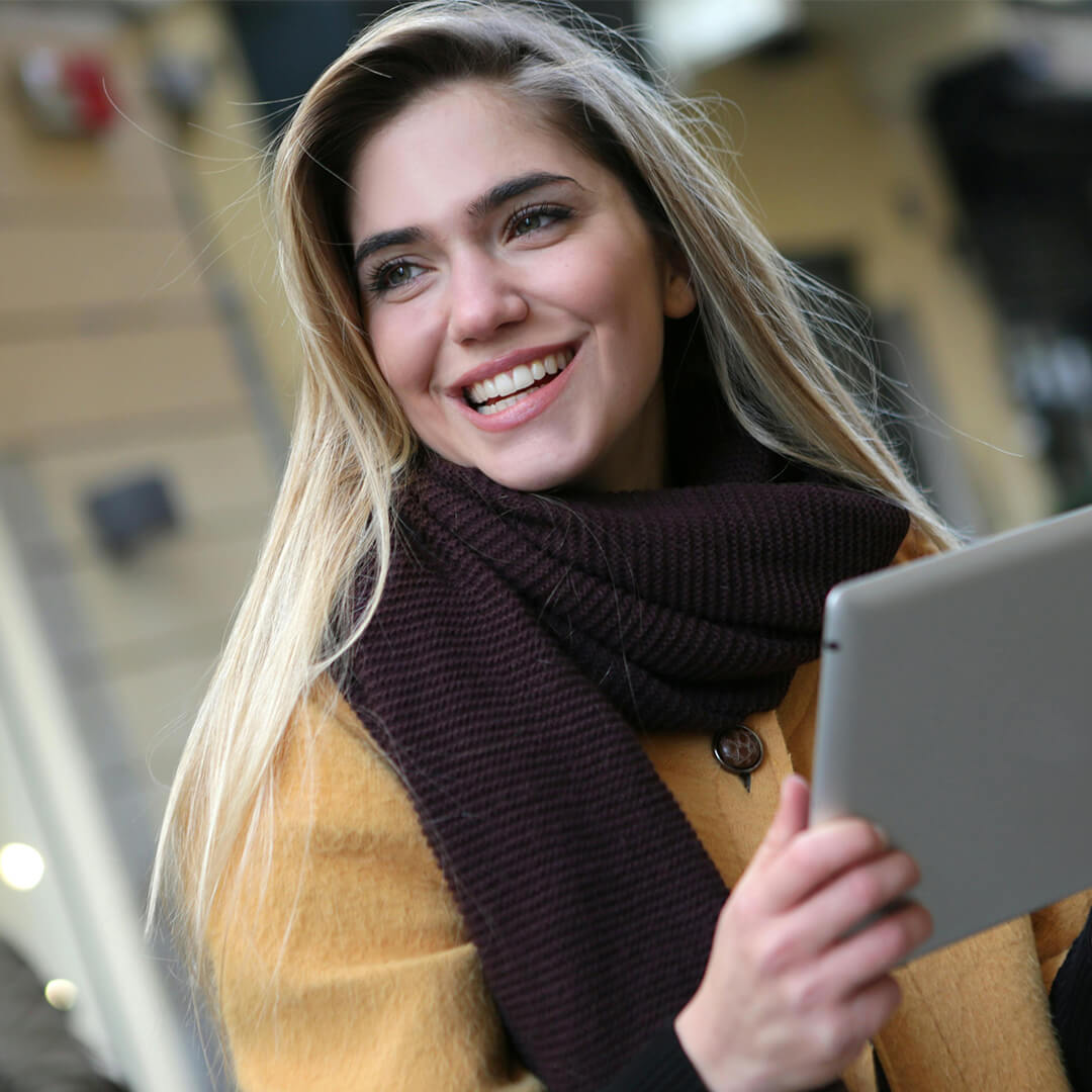 Young woman holding a smart tablet and smiling.