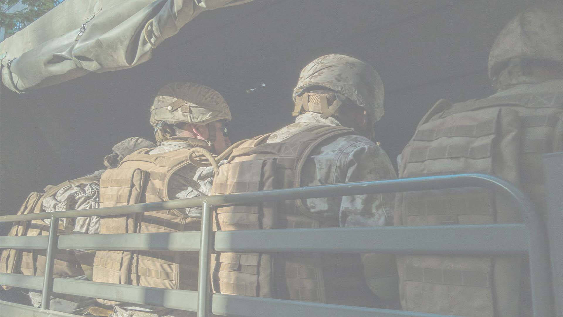 The back of four soldiers sat in a vehicle