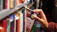 Close-up of someone grabbing a book from a full bookshelf