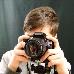 A close-up of a person holding Canon camera taking photograph