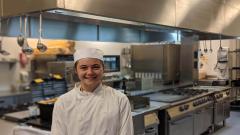 Catering student in chef whites stood in a kitchen