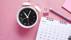 A calendrer and clock on a pink table 