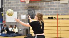 Someone throwing a netball inside a gym