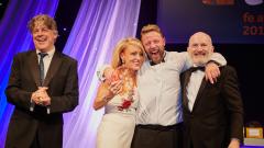 Alison Brightwell winning teacher of the year, on stage accepting her award, three men are also in the shot
