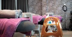 A row of three beauty salon beds with pink towels draped over them