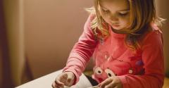 Young girl, wearing a pink top, reads a book