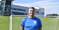 Darren Holloway stood in front of a football goal and EDC building