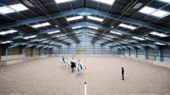 East Durham College's Equine Centre indoor arena with 4 blurred horses walking together
