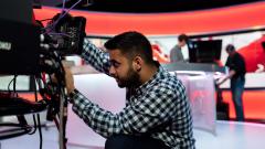 Male broadcast engineer working on a TV camera in a studio