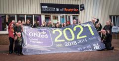 The Technical Academy Staff stood outside celebrating the college's fourth GOOD East Durham College Ofsted, holding a banner
