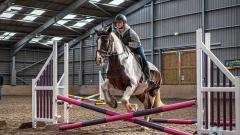 Student on horse leaping over fence