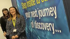 Two women standing in front of immersive room wall