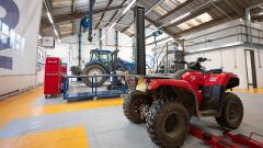 Landbased engineering workshop with red quad bike and blue tractor