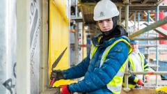 Bricklaying wearing high vis and hard hat looking into camera on building site