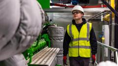 Young engineer in high visibility jacket and hard hat looking at machinery