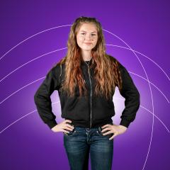 Female student with long brown hair standing with hands on hips against purple background