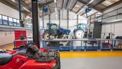 Workshop with red quad bike in foreground and blue tractor in background