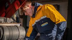 Engineer wearing boilersuit leaning over engine