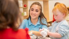 Smiling childcare student playing with children