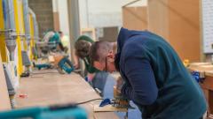 Student using saw to cut piece of wood on bench